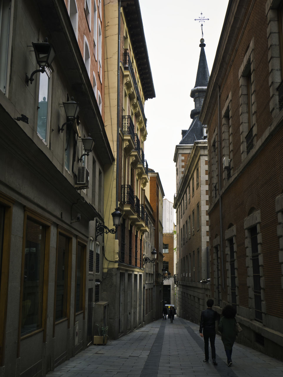 PEOPLE WALKING ON FOOTPATH AMIDST BUILDINGS IN CITY