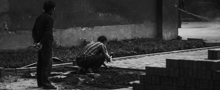 Rear view of people sitting on wall in city