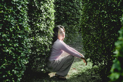 Woman looking away while standing against trees