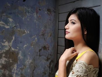 Portrait of woman standing against wall