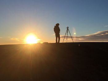 Silhouette man photographing against clear sky during sunset