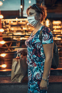Young woman walking along a store front after shopping in the city center in the evening