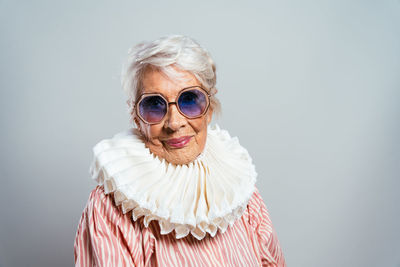 Portrait of young woman wearing sunglasses against wall