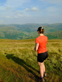 Rear view of woman standing on field against sky