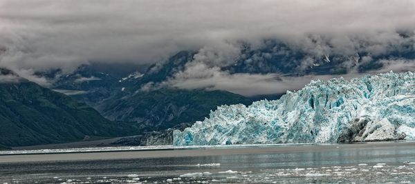 Scenic view of lake by snowcapped mountains against sky
