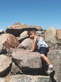 Full length of boy on rock against sky