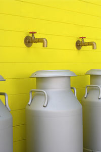 Close-up of white milk stainless steel bottles on yellow wood cottage background