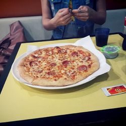 Cropped image of hand holding pizza on table in restaurant