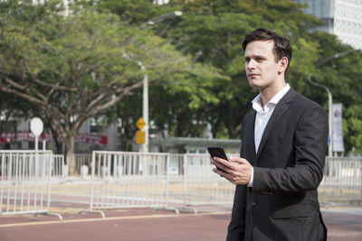 Young businessman using mobile phone in city