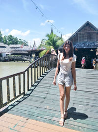 Full length of woman standing by railing against sky