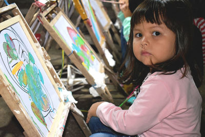 Close-up portrait of cute girl painting at school