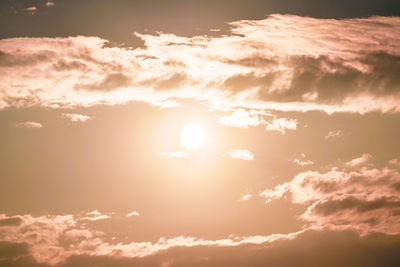 Low angle view of sunlight streaming through clouds