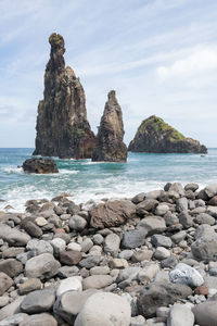 Rocks on sea shore against sky