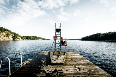 Woman relaxing by diving platform by lake