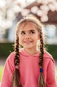 Portrait of cute smiling little girl with sly look in spring park. child enjoying playing outdoors