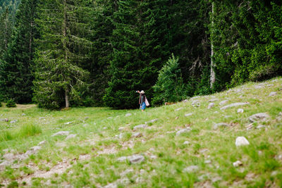 Woman hiking on field against trees in forest