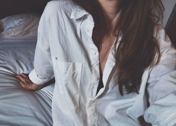 Midsection of woman relaxing on bed at home