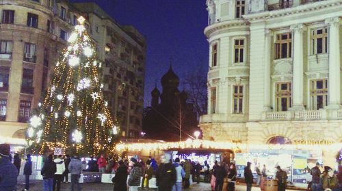 People at illuminated christmas lights at night