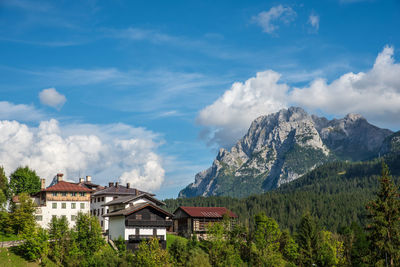 Houses by trees and mountains against sky