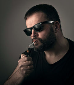Close-up portrait of man lighting cigarette