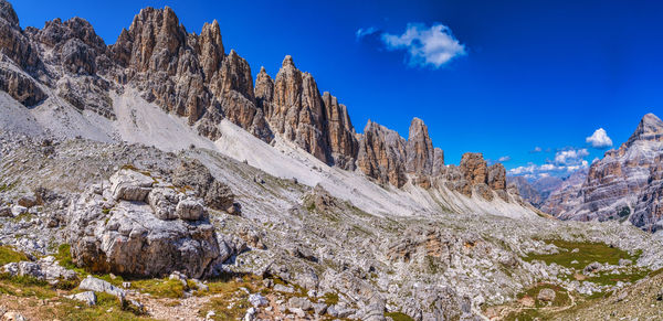 Panoramic view of rocky mountains against blue sky