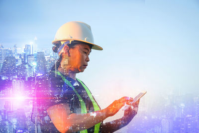 Digital composite image of man holding mobile phone against buildings in city