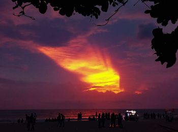 Silhouette people on beach against sky during sunset