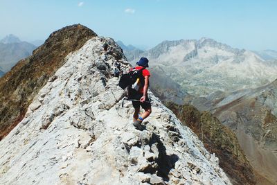 Rear view of men climbing on mountain against sky