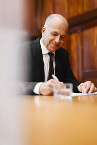 Smiling senior businessman signing contract document in board room