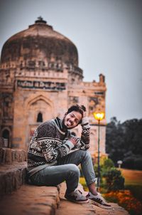 Full length of smiling woman sitting on temple