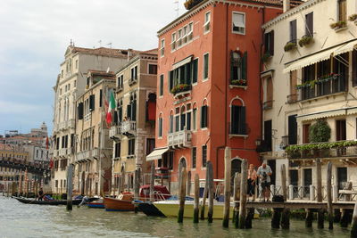 Buildings by canal against sky in city