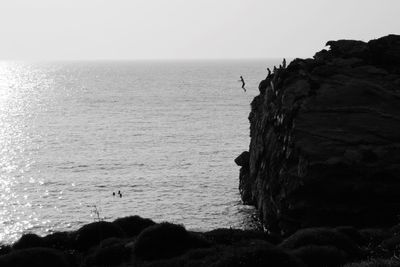 Rock formation by sea against clear sky