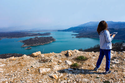 Rear view of woman standing on mountain against sky
