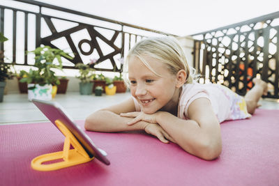 Smiling girl relaxing on the terrace looking at mobile phone