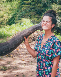 Smiling young woman holding elephant trunk