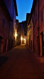 Empty road along buildings at night