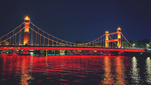 Illuminated bridge over river at night