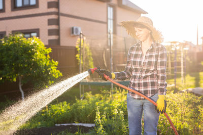 Person holding umbrella standing by plants