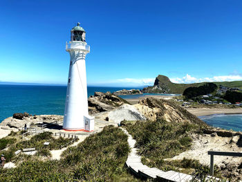 Lighthouse by sea against sky