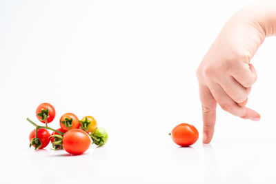 Close-up of hand holding strawberry over white background