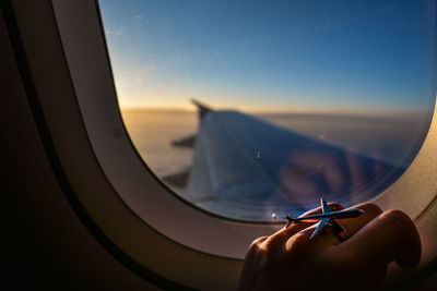 Cropped image of hand on window in airplane