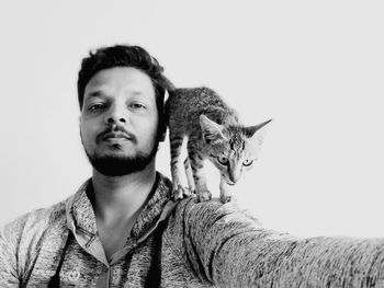 Portrait of man with cat against white background