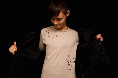 Young man standing against black background