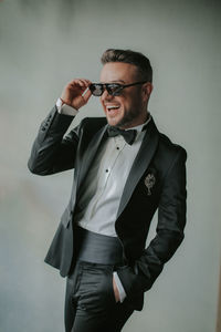 Young man wearing sunglasses standing against wall