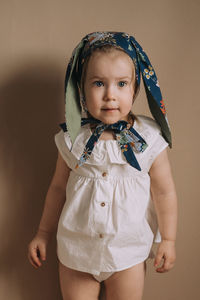 Toddler baby girl in funny hat with ears standing on monochrome background