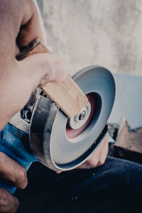 Midsection of man grinding wood with tool at workshop