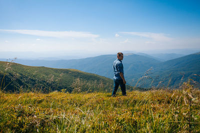 Man standing on field against mountain range