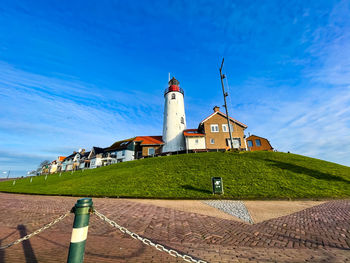 Low angle view of lighthouse by building against sky