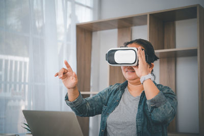 Woman gesturing while wearing virtual reality simulator at home