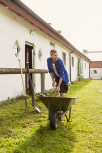 Smiling farmer removing equipment from wheelbarrow at farm